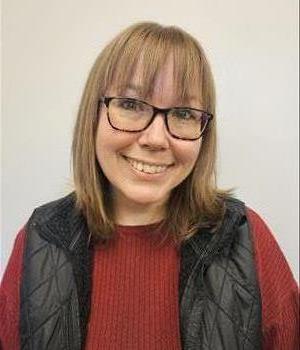 Woman with glasses and smiling in front of blue background