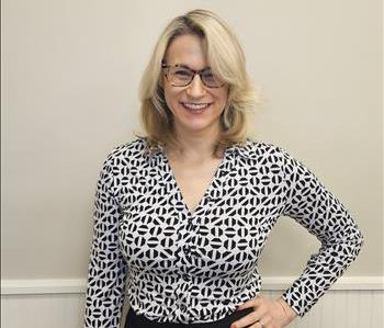 Woman with blonde hair and glasses against wall