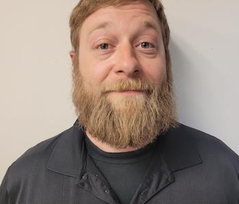 blond haired man against beige wall with blue eyes