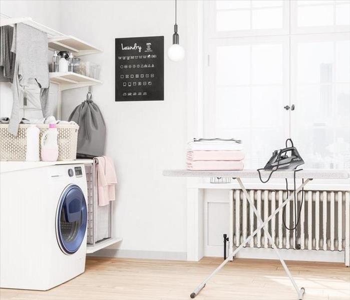 A white laundry room with a folding table and iron. 