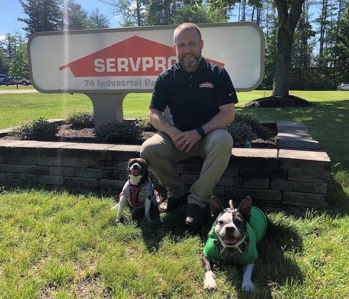 Owner and two dogs sitting in front of a SERVPRO sign